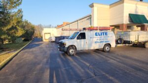 A white Elite HVAC service van is parked beside a commercial building on a paved lot in daylight, ready to support installation and maintenance of Building Automation Systems.