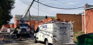 An Elite HVAC Solutions van is parked outside a well-maintained office complex in Moorestown, NJ. The image shows two technicians performing maintenance on outdoor HVAC units, ensuring efficient operation. The focus is on their professional demeanor and the cleanliness of the site, showcasing reliable commercial services.