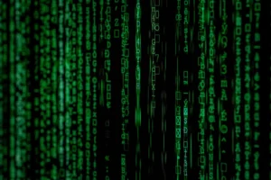 Green vertical lines of computer code and symbols cascade on a black background, resembling the digital rain effect from the Matrix movie—a fitting visual for the world of keeping data centers cool and efficient.