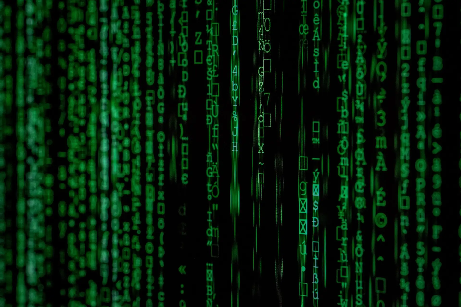 Green vertical lines of computer code and symbols cascade on a black background, resembling the digital rain effect from the Matrix movie—a fitting visual for the world of keeping data centers cool and efficient.