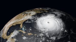 A large hurricane with a clearly defined eye is seen over the Atlantic Ocean approaching the eastern coast of the United States, where rising humidity poses a hidden toll on communities and commercial buildings alike, as viewed from space.