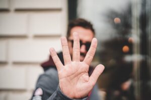 A person stands outdoors with an open hand held up toward the camera, obscuring their face and creating one of those unusual moments. The background is slightly blurred.
