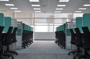 Rows of empty office chairs and desks in a modern office space with large windows and bright overhead lighting—an ideal setting for Commercial HVAC efficiency, ready to handle even the most Unusual HVAC Moments in 2025.