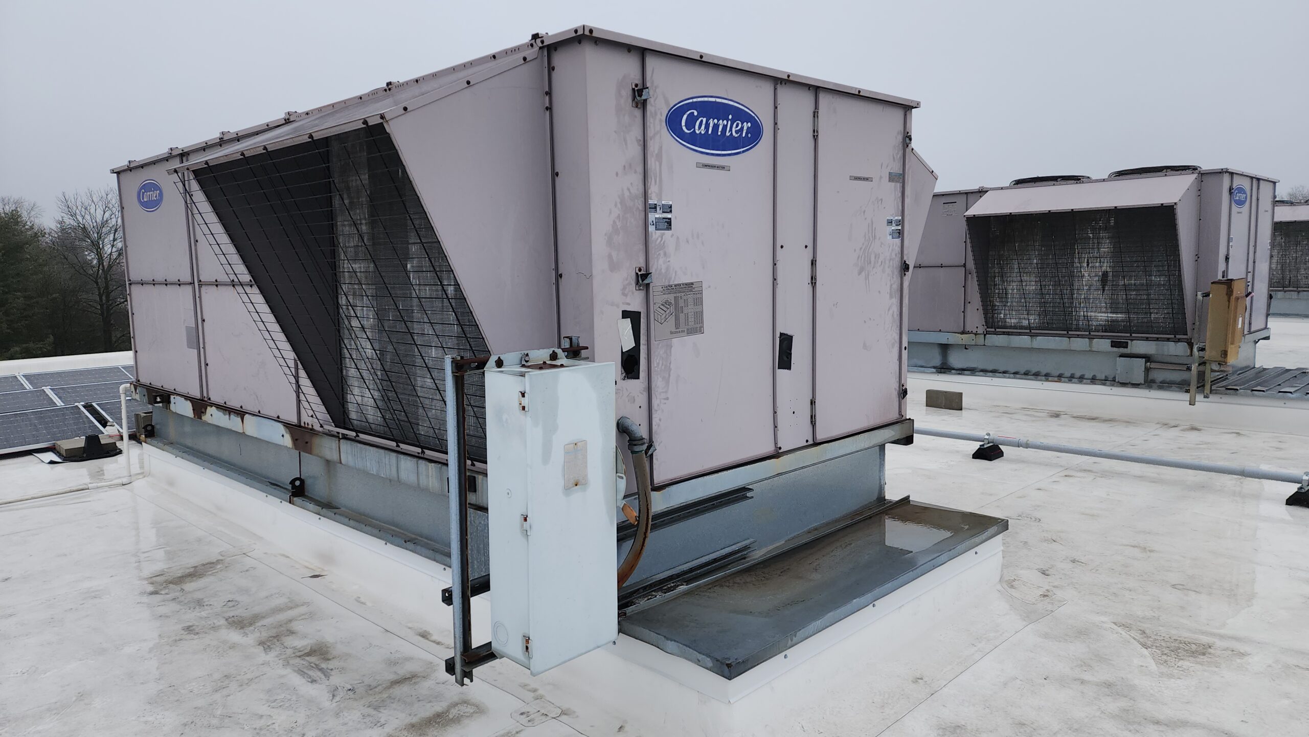 Large commercial HVAC units with Carrier branding sit atop a flat white roof under an overcast sky—capturing one of those unusual moments in 2025 when cutting-edge comfort meets industrial design.