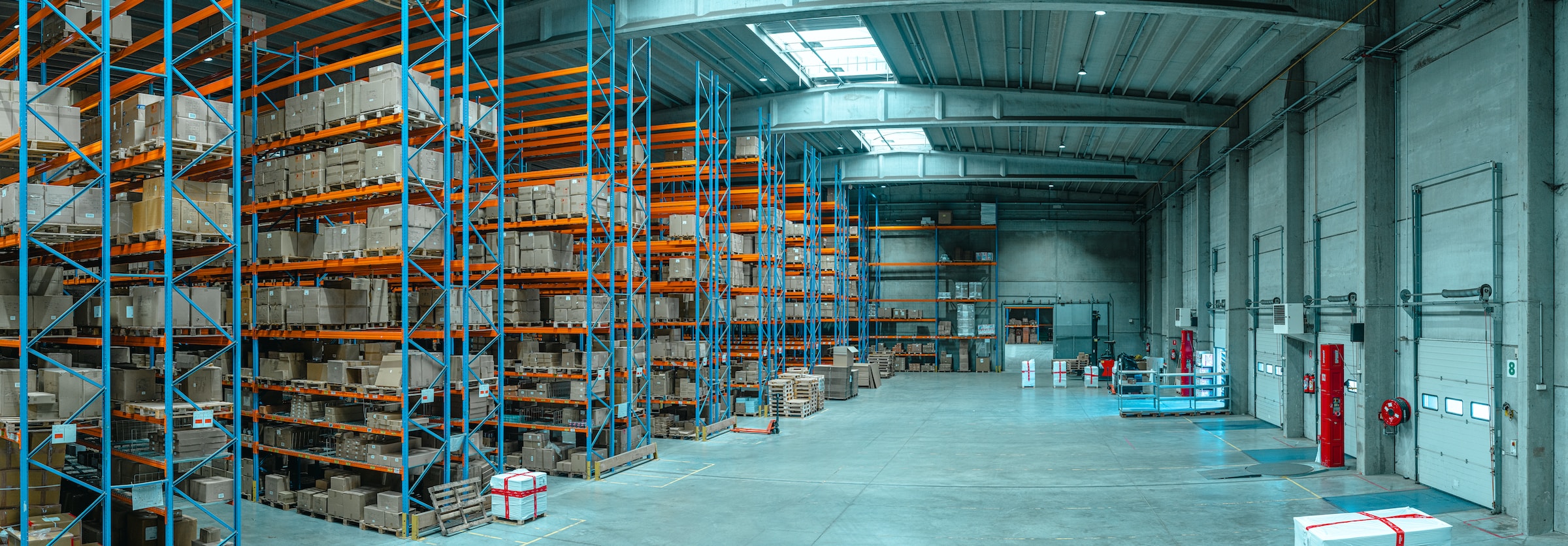 Large warehouse interior with high shelves filled with boxes and pallets, concrete floors, loading docks, and commercial HVAC for optimal climate control—ready to handle any unusual moments that 2025 may bring.
