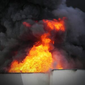 Large flames and thick black smoke rise from a burning building, partially visible at the bottom of the image.