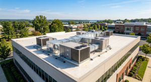 Aerial view of a commercial building rooftop with multiple HVAC units, engineered to stop corrosionāan ideal solution for South Jersey businesses, surrounded by trees and other office buildings on a clear day.